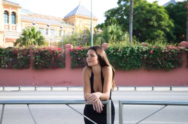 pretty young Spanish woman looking over the railing to the horizon. The woman is happy and content because she looks to the future with interest.