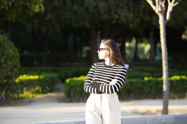 Uzun Kahverengi Saçlı Siyah Beyaz Tişörtlü Beyaz Pantolonlu Güneş Gözlüklü — Stok fotoğraf