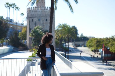 Gayri resmi giyinmiş, siyah saçlı güzel bir kadın Seville, İspanya 'da. Kadın mutlu ve gülümsüyor. Tatil boyunca şehrin sunduğu manzaranın tadını çıkarıyor..