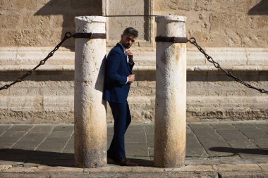 Sakallı, mavi takım elbiseli ve kravatlı yakışıklı bir genç. İspanya 'daki Sevilla katedralinin sütununa yaslanıyor. Bu adam şehirde bir iş gezisinde olan bir yönetici.