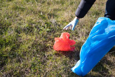 Ormandan kırmızı plastik bir poşet alan bir gönüllüyle ilgili detaylar. Dünya Günü ve Dünya Çevre Günü kavramı 5 Haziran.