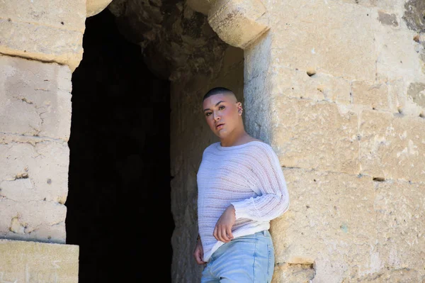 Non binary latin and young person, is in a castle making different body expressions in the hole of the door. Concept of diversity, homosexuality and gay pride