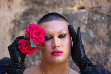 Siyah makyaj ve siyah kanatlar takmış, elinde tuttuğu yüzünün yanında iki kırmızı gülle ikili olmayan genç bir Latin 'in portresi. İfade ve duygu kavramı