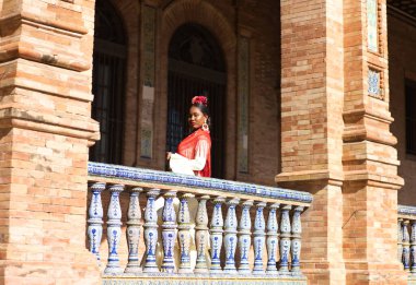 İspanya, Seville 'de bir meydanda flamenko çingenesi gibi giyinmiş genç siyahi bir kadın. O, fırfırlı bej bir elbise ve çiçekli kırmızı bir şal giyer. İnsanlığın Flamenko kültürel mirası. Dans konsepti