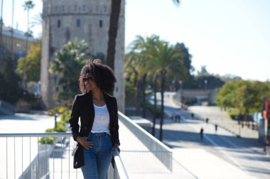 Gayri resmi giyinmiş, siyah saçlı güzel bir kadın Seville, İspanya 'da. Kadın mutlu ve gülümsüyor. Tatil boyunca şehrin sunduğu manzaranın tadını çıkarıyor..