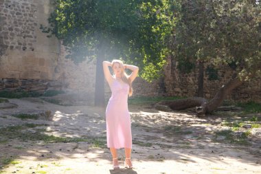 Genç ve güzel sarışın kadın İspanya 'da ortaçağ şatosunda rahatça yürüyor. Kadın uzun bir menekşe elbise giyiyor. Seyahat ve tatil konsepti