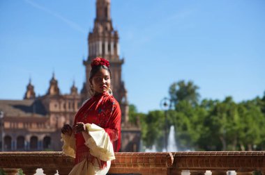 İspanya, Seville 'de bir meydanda flamenko çingenesi gibi giyinmiş genç siyahi bir kadın. O, fırfırlı bej bir elbise ve çiçekli kırmızı bir şal giyer. İnsanlığın Flamenko kültürel mirası. Dans konsepti