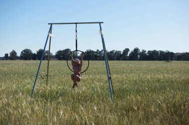 Genç ve güzel sarışın kadın çemberde aerobik egzersizleri yapıyor. Kafasında kansere karşı pembe bir eşarp var, kırsalda bir buğday tarlasında. Sağlık ve spor konsepti