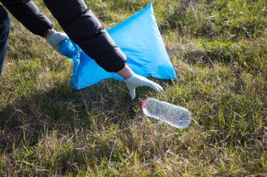 Ormandan geri dönüşüm çantasına koymak için plastik şişe toplayan bir gönüllüyle ilgili detaylar. Dünya Günü ve Dünya Çevre Günü kavramı 5 Haziran.