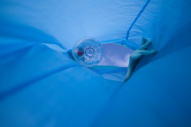 Detail of a volunteer's hand putting a plastic bottle in the bag. Photo taken from below. Concept of Earth Day and World Environment Day June 5.