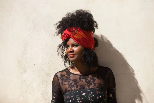 Portrait of a young, beautiful black woman with afro hair and black dress with flowers, wearing a red scarf in her hair. The woman is happy and laughing and having fun. Concept different expressions