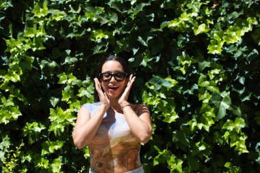 Genç ve güzel esmer, esmer ve Latin saçlı kadın Seville 'de tatilde. Kadın, elleri yüzünde, hayranlık, şaşkınlık ve mutlulukla farklı ifadeler kullanır.