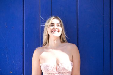 Arka planda mavi kapılı güzel sarışın kadın farklı ifadeler kullanır ve gülümseyerek eğlenir. Kavramsal mutluluk kavramı