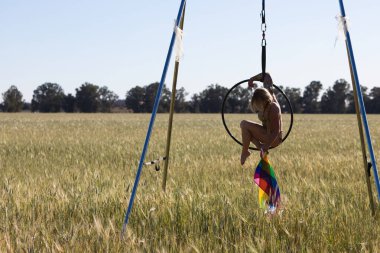 Genç ve güzel sarışın bir kadın çemberin üzerinde aerobik egzersizleri yapıyor, elinde geylerin ve lezbiyenlerin haklarını talep eden eşcinsel gurur bayrağı var. Gey gururu kavramı