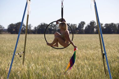 Genç ve güzel sarışın bir kadın çemberin üzerinde aerobik egzersizleri yapıyor, elinde geylerin ve lezbiyenlerin haklarını talep eden eşcinsel gurur bayrağı var. Gey gururu kavramı