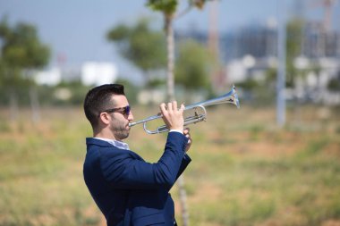 Sakallı, mavi takım elbiseli, trompet çalan yakışıklı bir iş adamı. Adam boş zamanlarında bir müzisyen ve müzik onun en büyük tutkularından biri.