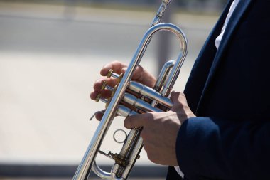 Müzikal enstrüman çalan bir trompetçinin elleri. El, trompetin pistonlarını kaldırır ve alçaltır. 1 Ekim uluslararası müzik günü.