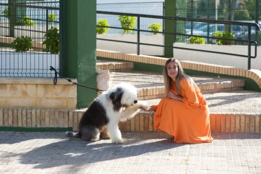Deniz kıyısındaki balıkçıların teknelerinde oturan güzel sarışın kadın. Ufuktaki arka planda mavi deniz ve denizde çalışan tekneler. Tatil ve seyahat kavramı