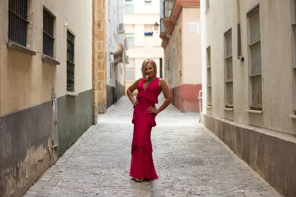 Zarif bir elbise giymiş güzel, sarışın, olgun bir kadın manken gibi caddede dolanıyor. Kadın mutlu ve günün tadını çıkarıyor.