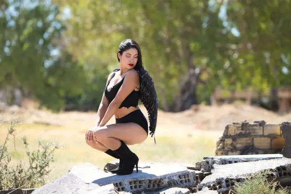 Siyah kanatlı, genç, güzel, siyah saçlı bir Latin kadın savaş ve kıyametin mahvettiği bir şehrin kalıntıları arasında duruyor. Üzüntü ve kederle etrafına bakıyor.