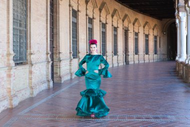 Endülüs, Seville Plaza de Espana 'da tipik yeşil elbiseli ve dans eden genç ve güzel bir kadın sanat ve tutkuyla yürüyor. 16 Kasım, uluslararası flamenko günü