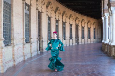 Endülüs, Seville Plaza de Espana 'da tipik yeşil elbiseli ve dans eden genç ve güzel bir kadın sanat ve tutkuyla yürüyor. 16 Kasım, uluslararası flamenko günü