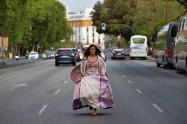 15. yüzyıldan kalma uzun kıvırcık saçlı güzel bir Latin kadın büyük bir caddede arabaların arasında koşuyor. Kadın geçmişten bugüne zamanda yolculuk yapıyor.