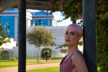 Pembe saçlı, makyajlı ve pembe giyinmiş genç bir eşcinsel parkta bir afişe yaslanıyor. Çocuk ayrımcılık yüzünden üzgün ve depresif. Eşitlik ve LGBTQ hakları kavramı