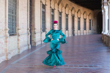 Endülüs, Seville Plaza de Espana 'da tipik yeşil elbiseli ve dans eden genç ve güzel bir kadın sanat ve tutkuyla yürüyor. 16 Kasım, uluslararası flamenko günü