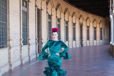 Endülüs, Seville Plaza de Espana 'da tipik yeşil elbiseli ve dans eden genç ve güzel bir kadın sanat ve tutkuyla yürüyor. 16 Kasım, uluslararası flamenko günü