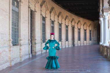 Endülüs, Seville Plaza de Espana 'da tipik yeşil elbiseli ve dans eden genç ve güzel bir kadın sanat ve tutkuyla yürüyor. 16 Kasım, uluslararası flamenko günü