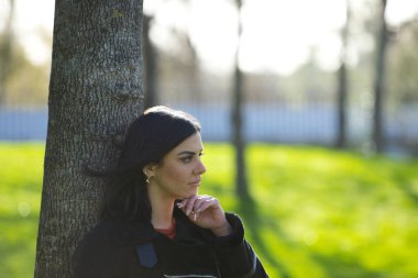 Kısa saçlı, kısa kotlu, siyah ceketli, soğuk bir günde yapraksız ağaca yaslanan genç ve güzel esmer kadın depresyondan dolayı ciddi ve üzgün. Zihin Sağlığı