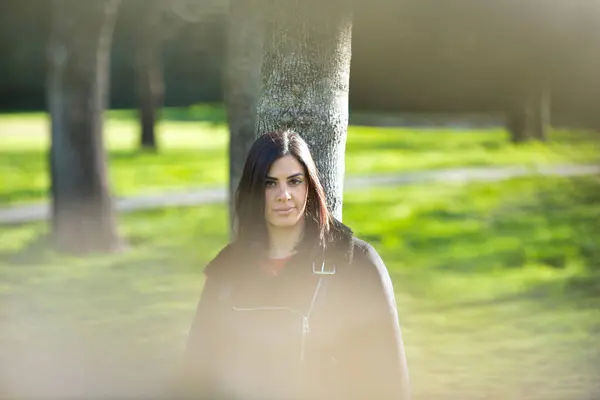 Kısa saçlı, kısa kotlu, siyah ceketli, soğuk bir günde yapraksız ağaca yaslanan genç ve güzel esmer kadın depresyondan dolayı ciddi ve üzgün. Zihin Sağlığı