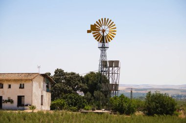 An American farm with a windmill is an iconic image that evokes rural life and connection to nature. These windmills are typical and referential in the agricultural world. Renewable energy concept clipart