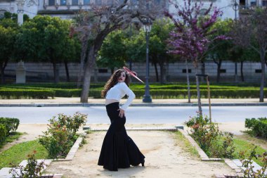 Uzun kıvırcık saçlı, kızıl yelpazeli flamenko dansı yapan güzel bir kadın Sevilla, İspanya 'da. Uzun siyah etek, beyaz gömlek giyiyor ve farklı dans pozları veriyor. İnsanlığın kültürel mirası