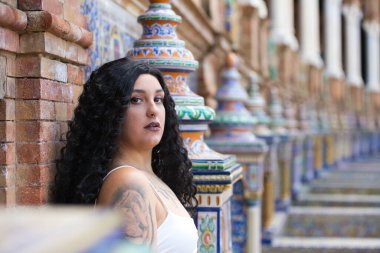 Genç, güzel, şişman, kıvrımlı, uzun kıvırcık, kahverengi saçlı, beyaz elbiseli, İspanya meydanındaki fayanslı banklarda oturan, farklı ifadeler kullanan lezbiyen kadın.