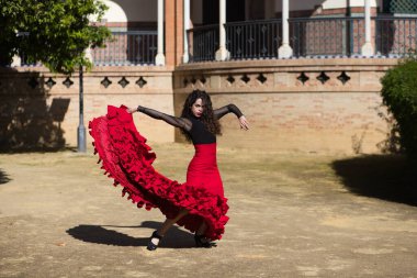 İspanya, Sevilla 'da flamenko dansı yapan güzel bir kadın. Flamenko dansçısının tipik kırmızı ve siyah bir elbisesi var. Bir sürü sanatı var. Fırfırlı elbisenin havasındaki hareketi görebilirsiniz..