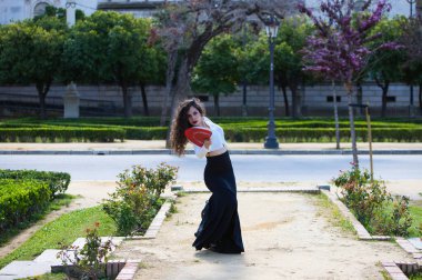 Uzun kıvırcık saçlı, kızıl yelpazeli flamenko dansı yapan güzel bir kadın Sevilla, İspanya 'da. Uzun siyah etek, beyaz gömlek giyiyor ve farklı dans pozları veriyor. İnsanlığın kültürel mirası