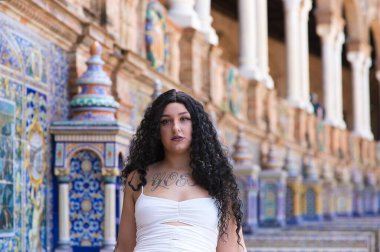 Genç, güzel, şişman, kıvrımlı, uzun kıvırcık, kahverengi saçlı, beyaz elbiseli, İspanya meydanındaki fayanslı banklarda oturan, farklı ifadeler kullanan lezbiyen kadın.