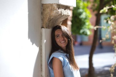 Genç ve güzel Latin bir kadın şehir geçidinde bir duvara yaslanıyor. İspanya 'nın Sevilla şehrinde kadın mutlu ve gülümsüyor.