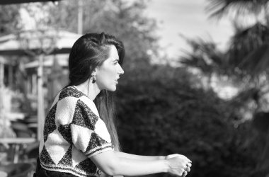 Demir korkuluklara yaslanan genç ve güzel Latin kadın nehri geçerken üzgün ve depresif görünüyor. Kadın dalgın, bitkin ve yorgun görünüyor. Kadın acı çekiyor. Tek renkli fotoğraf.