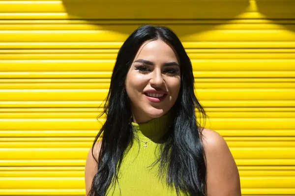 Genç İspanyol kadın, esmer ve güzel sarı arka planda yeşil elbisesi var gülümsüyor ve çok mutlu. 20 Haziran, yılın en mutlu günü. Mutluluk ve neşe kavramı