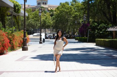 Genç İspanyol kadın, esmer ve beyaz elbiseli güzel kadın Seville, İspanya 'nın merkezindeki yaya geçidinde farklı vücut duruşları sergiliyor. Güzellik ve moda konsepti