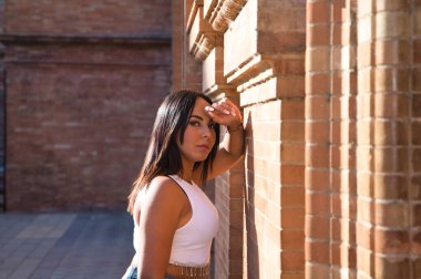 Genç ve güzel esmer kadın başını duvara yaslamış ve kameraya bakmış. Kadın üzgün, depresyonda ve acı ve umutsuzluk hissediyor. Kendini kötü ve negatif hissediyor.