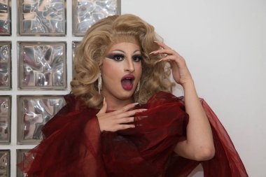 Sarı peruklu, lüks küpeli, kırmızı ipek kapaklı, cam kapaklı ve farklı ifadeler kullanan bir travesti. Üzgün, mutlu, sürpriz, kayıtsız. lgtbqi hakları ve eşitliği kavramı