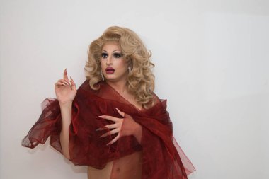 Sarı peruklu, lüks küpeli, kırmızı ipekle kaplanmış ve beyaz arka planda farklı ifadeler kullanan bir travesti. Üzücü, mutlu, sürpriz. lgtbqi hakları ve eşitliği kavramı