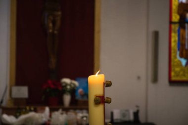 Katolik kilisesi. Paschal mumu. Paskalya 'da her yıl yeni bir Paskalya mumu kutsanır ve yakılır. Arka planda tahta bir İsa.