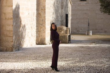 İspanya 'nın Seville kentindeki bir köyde, bir manastırın yanındaki kaldırım taşından bir sokakta poz veren zarif mor elbiseli güzel bir genç kadın. Kadın farklı ifadeler ve jestler yapıyor.