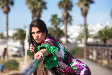 Latin bir kadın, genç ve güzel dans eden flamenko saçları havada elini ve kolunu korkuluklara uzatıyor. Dalgalı ve çiçekli beyaz elbiseli kadın tipik Endülüs.