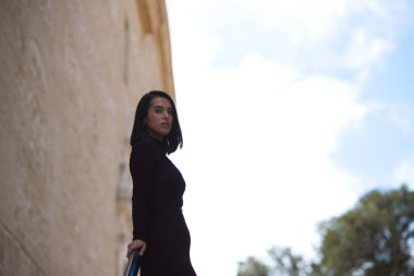 Genç ve güzel bir kadın zarif bir menekşe elbise giyip merdivenlere yaslanmış, farklı yerlere bakıyor. Depresyonda ve üzgün olduğu için. Ruh sağlığı konsepti.